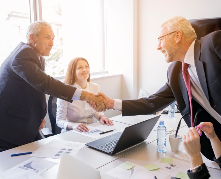 Professionals shaking hands over a contract, symbolizing partnerships.